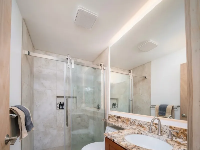 Bathroom renovation Maui — walk-in tile shower, granite vanity and backlit mirror