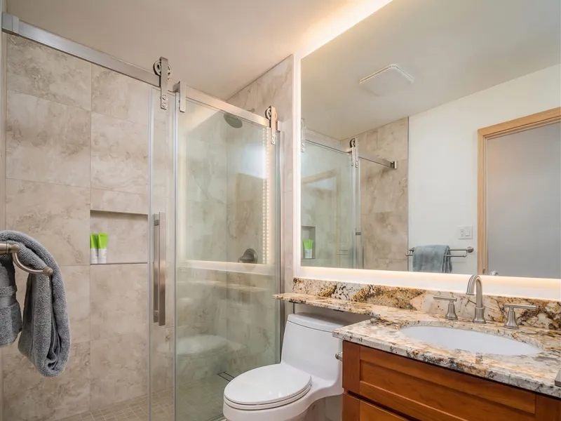 Bathroom renovation Kihei Maui — full tile shower with frameless glass door and granite countertop