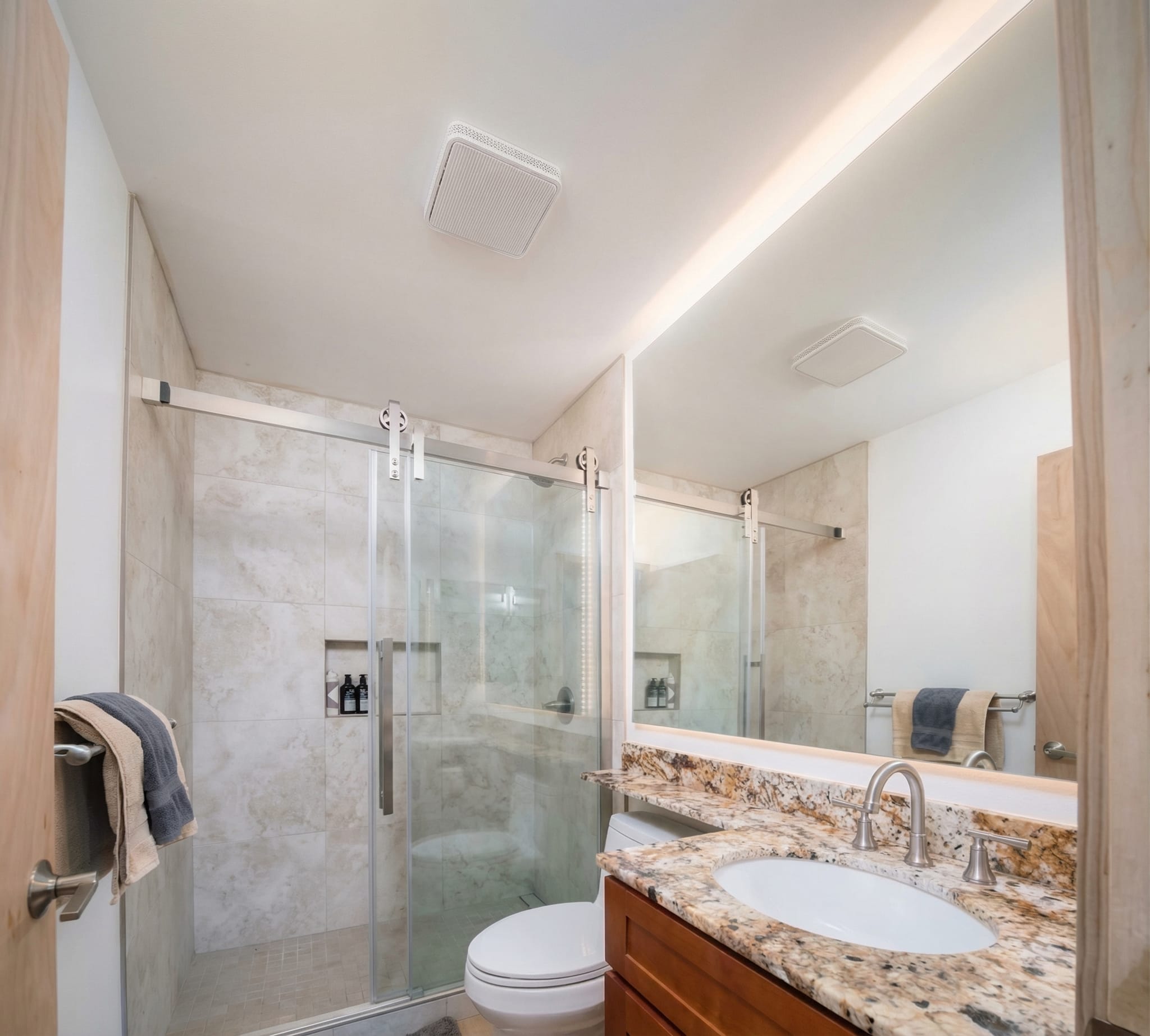 Bathroom renovation Maui — walk-in tile shower, granite vanity and backlit mirror
