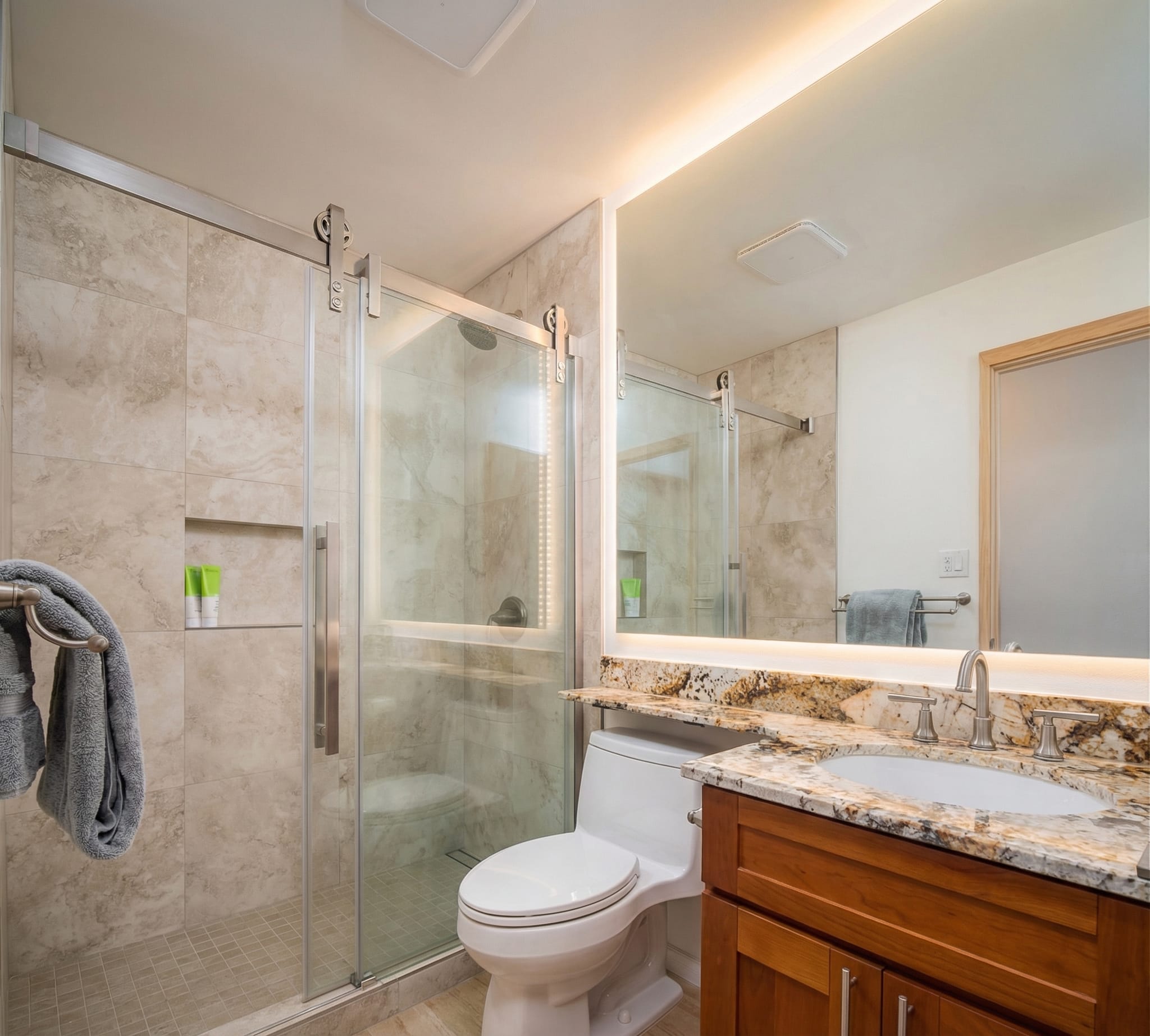Bathroom renovation Kihei Maui — full tile shower with frameless glass door and granite countertop
